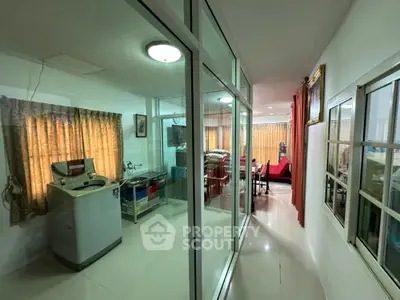 Spacious interior with glass partitions and modern furnishings, featuring a washing machine and cozy living area.