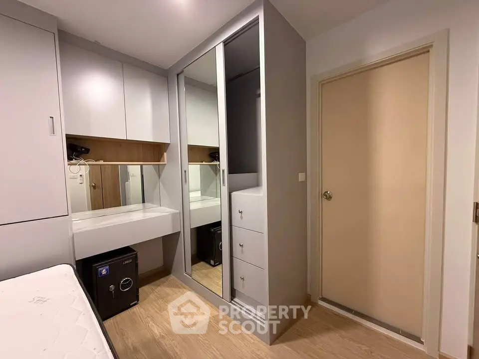 Modern bedroom with sleek mirrored wardrobe and built-in desk in stylish apartment.
