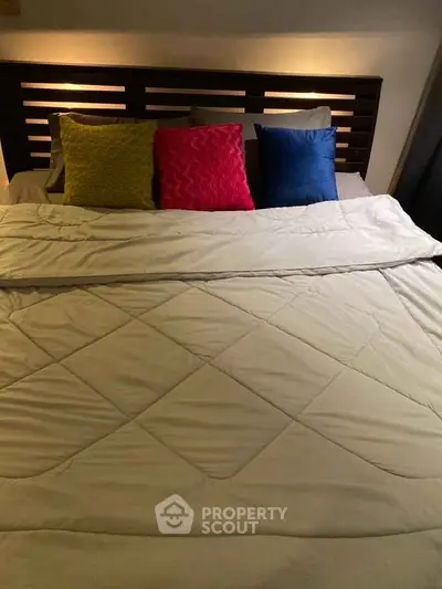 Cozy bedroom with colorful pillows and modern headboard design.