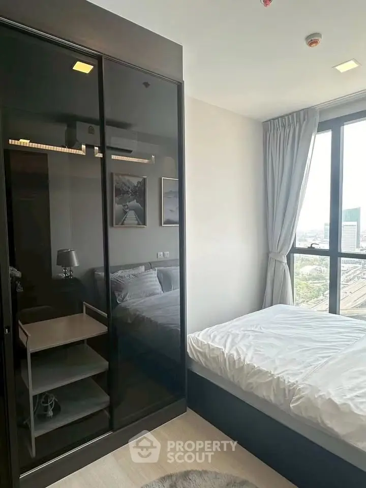 Modern bedroom with large window and sleek black wardrobe in a high-rise apartment.