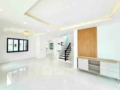 Spacious modern living room with elegant ceiling lights and sleek staircase in a bright open layout.