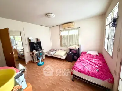 Spacious bedroom with twin beds and natural light, ideal for comfortable living.