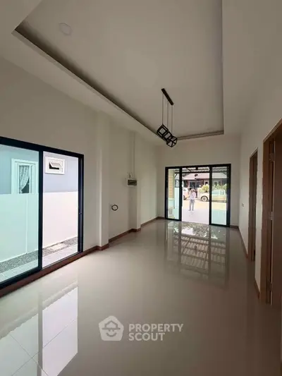 Spacious modern living room with large windows and glossy tiled floors
