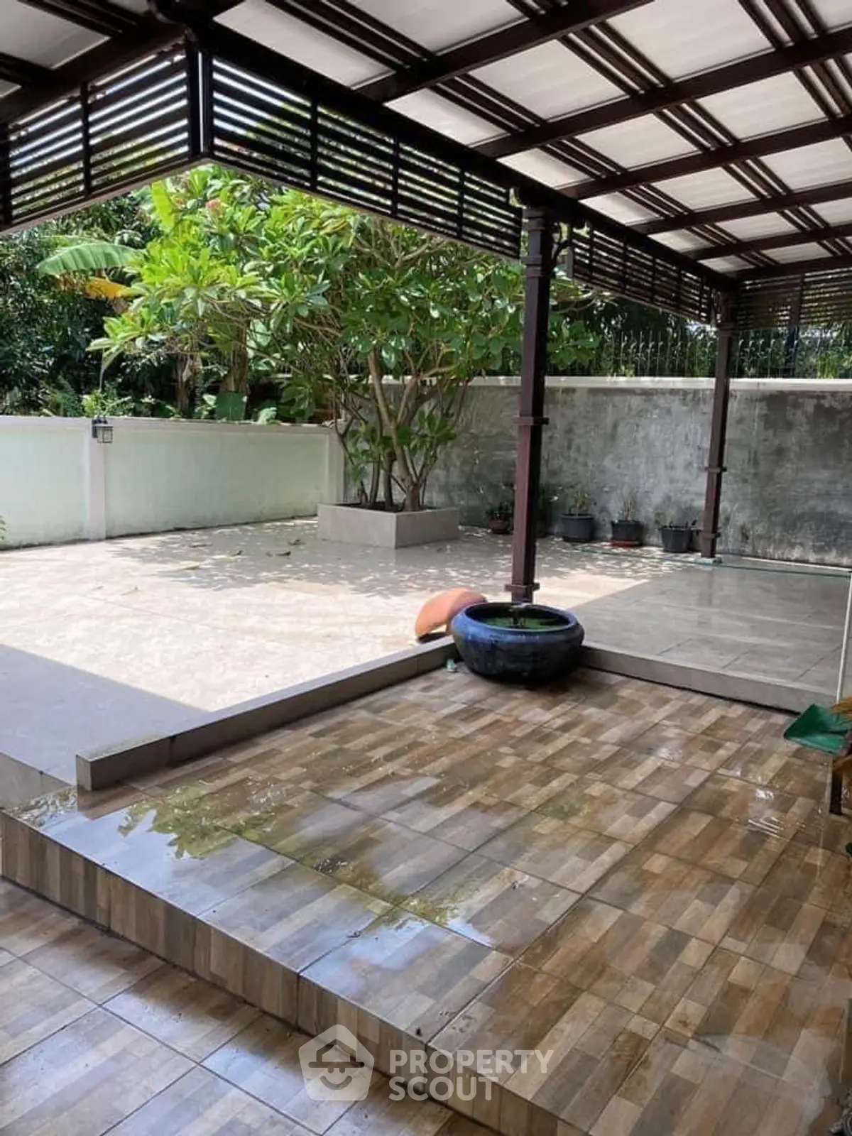 Spacious outdoor patio with modern pergola and lush greenery