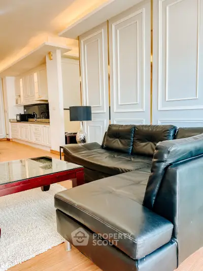 Modern living room with sleek black leather sofa and stylish kitchen in open layout
