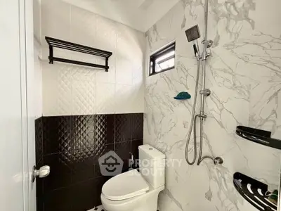 Modern bathroom with stylish black and white tiles and sleek shower fixtures.