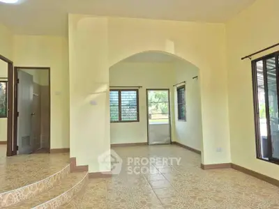 Spacious living room with tiled floors and large windows offering natural light in a modern home.