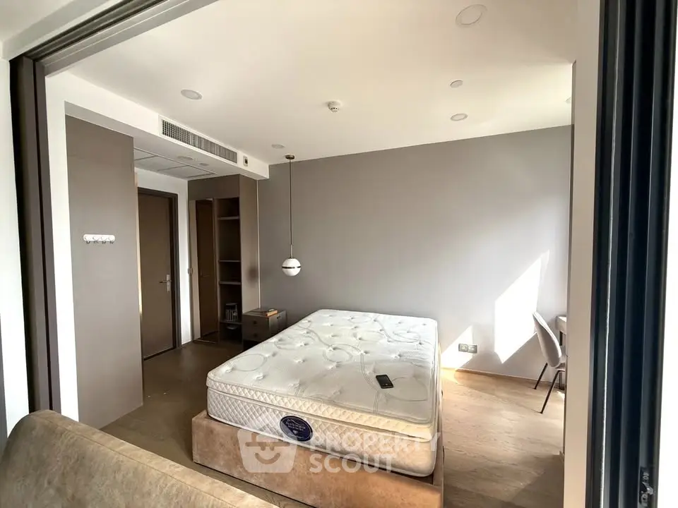 Spacious bedroom with modern decor and natural light, featuring a comfortable bed and stylish furnishings.