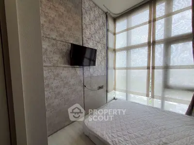 Modern bedroom with wall-mounted TV and large windows with sheer curtains