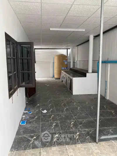 Spacious utility area with tiled flooring and open window, ideal for laundry or storage.