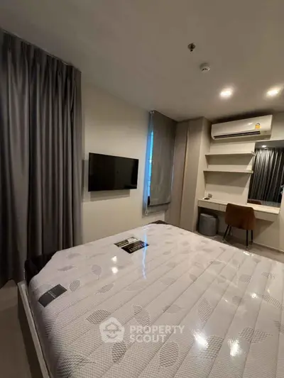 Modern bedroom with wall-mounted TV and air conditioning in stylish apartment.