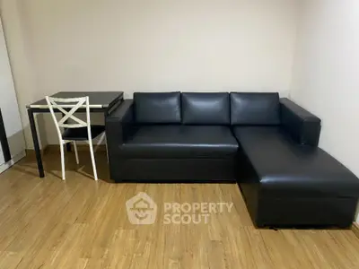 Modern living room with sleek black leather sofa and wooden flooring