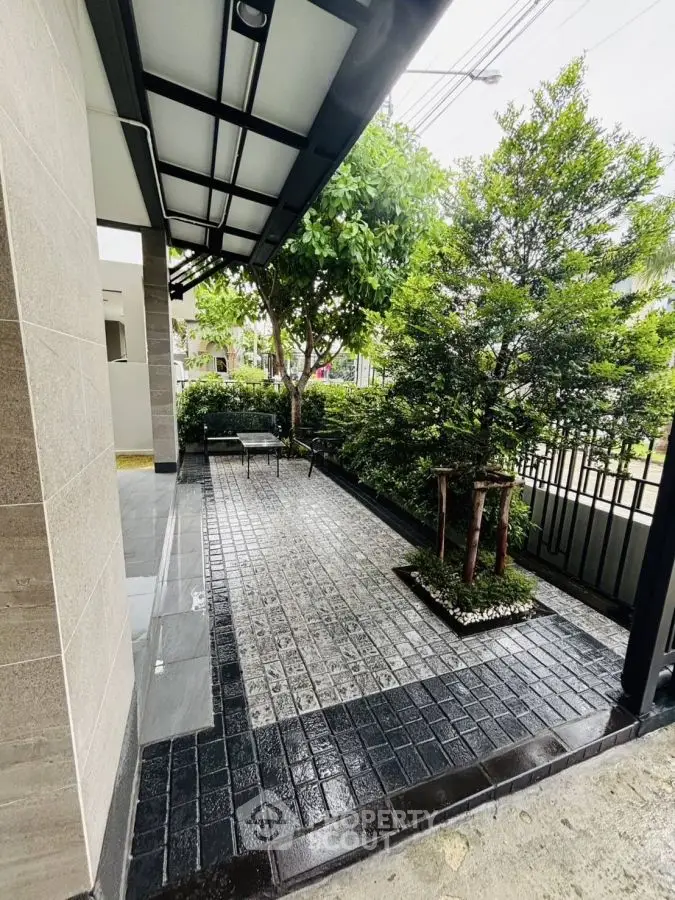 Charming garden entrance with lush greenery and modern stone pathway.