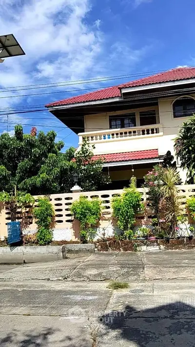 Charming two-story house with red roof and lush garden in a serene neighborhood.