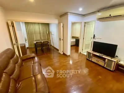 Spacious living room with wooden flooring and modern furniture in a cozy apartment.