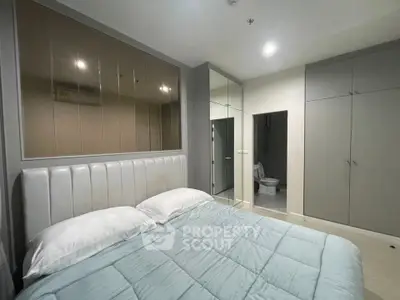 Modern bedroom with mirrored closet and ensuite bathroom in stylish apartment