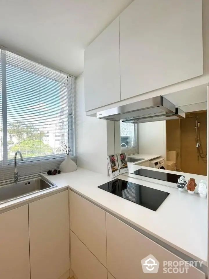 Modern kitchen with sleek design and large window offering natural light