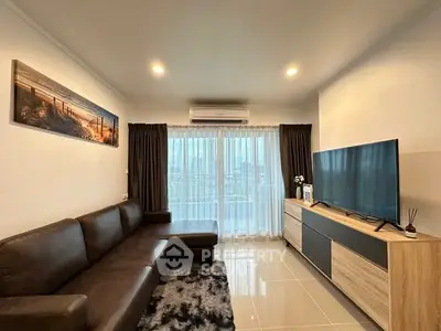 Modern living room with sleek leather sofa and large TV, featuring elegant decor and natural light.