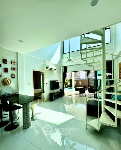 Stunning open-plan living room with spiral staircase and pool view, perfect for modern living.