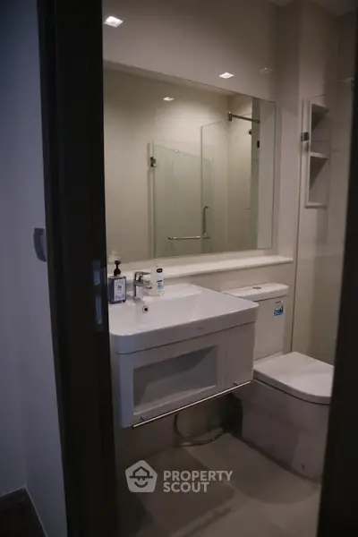Modern bathroom with sleek fixtures and large mirror in contemporary apartment.