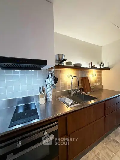Modern kitchen with sleek stainless steel countertops and built-in appliances.