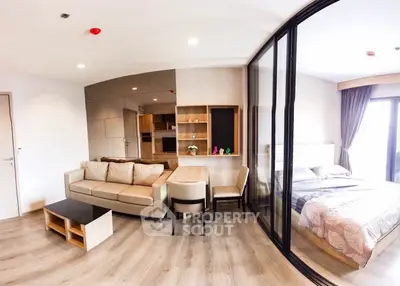 Modern open-plan living room with glass partition and cozy bedroom