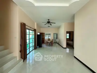 Spacious open-plan living area with ceiling fan and dining space, featuring large windows for natural light.