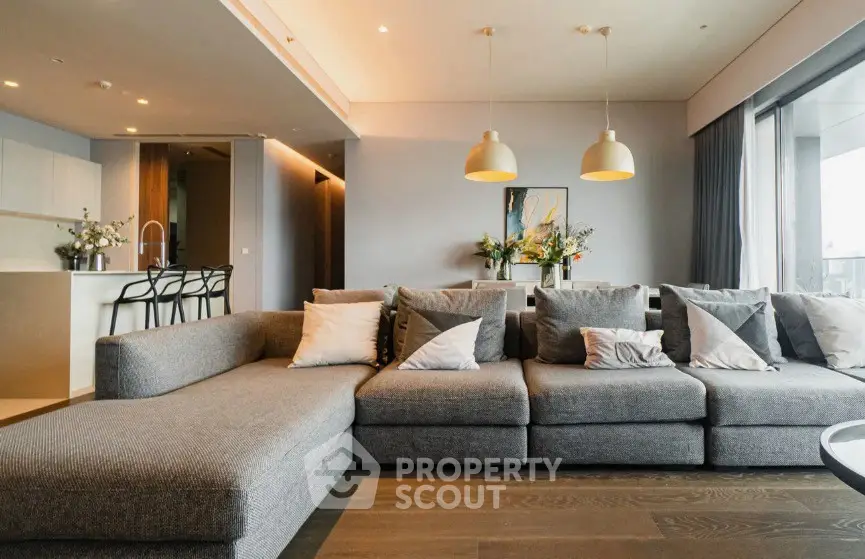 Spacious modern living room with stylish gray sectional sofa and open kitchen layout.