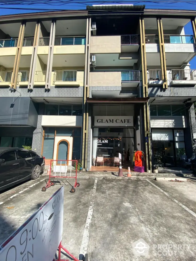 Modern commercial building with Glam Cafe on ground floor and parking space in front.