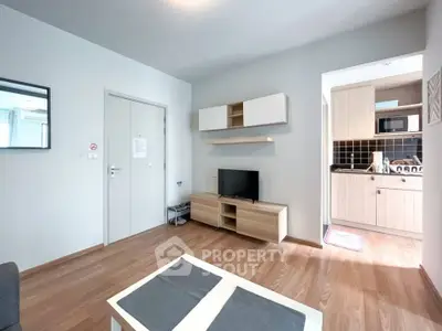 Modern living room with sleek kitchen, wooden flooring, and stylish furniture in a cozy apartment.