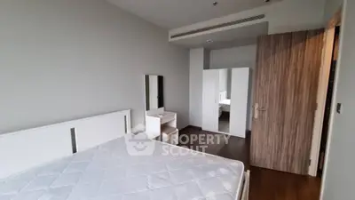 Modern bedroom with minimalist furniture and large mirror reflecting natural light.