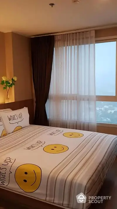 Cozy bedroom with a cheerful emoji-themed bedding set, large windows offering ample natural light, and a warm ambiance perfect for relaxation.