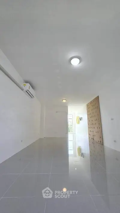 Spacious modern living room with glossy tiled floors and air conditioning unit.