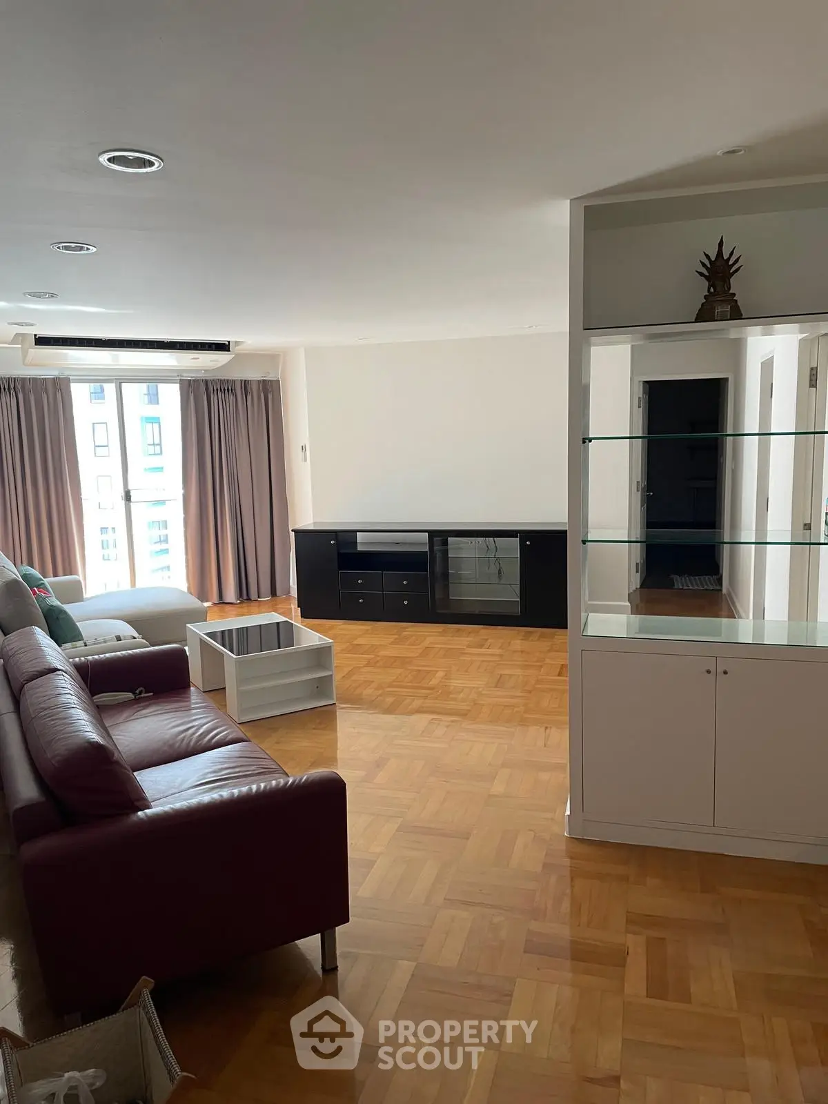 Spacious living room with parquet flooring and modern furniture in a bright apartment.