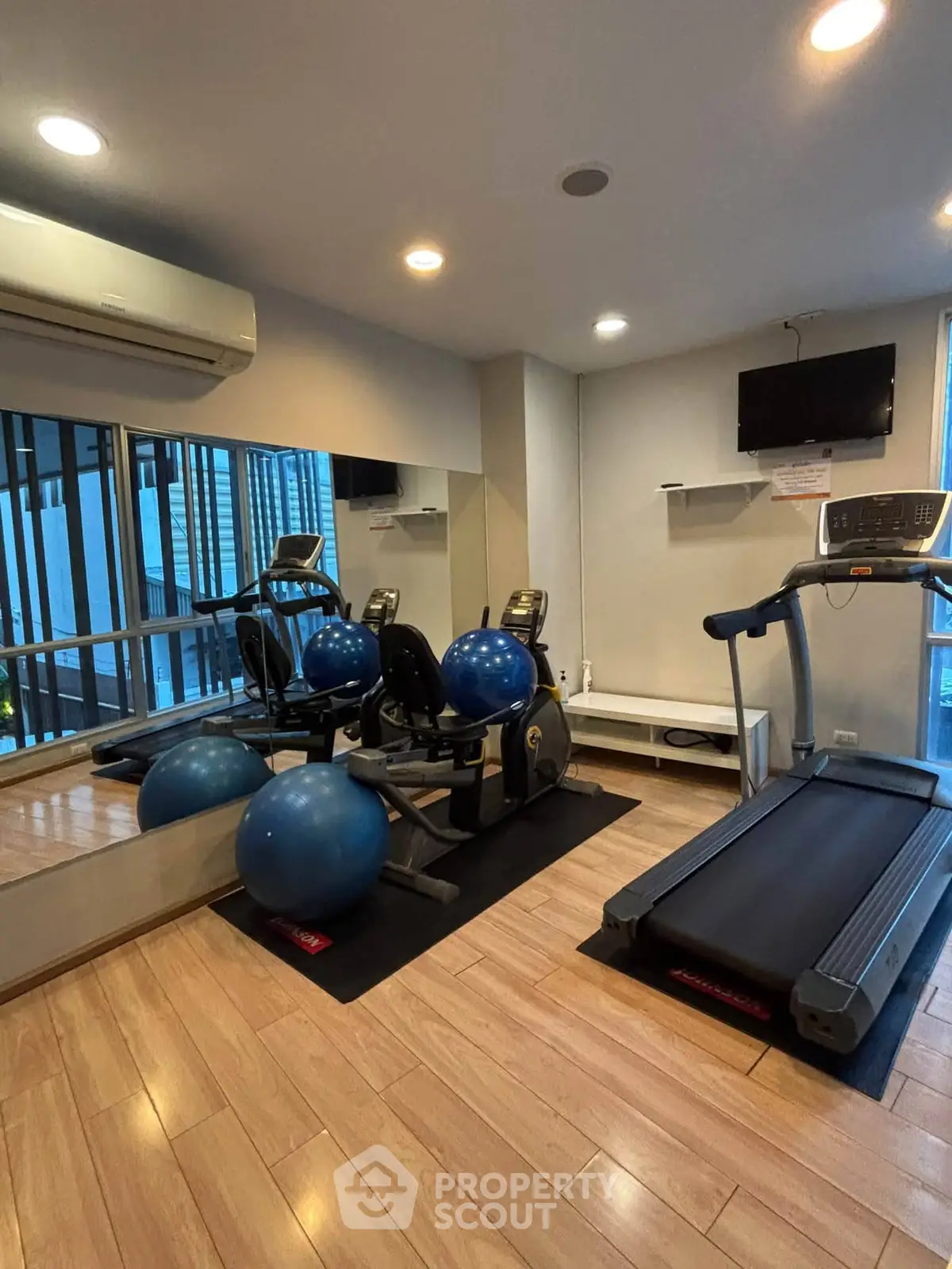 Modern gym with treadmill, exercise bikes, and fitness balls in a sleek residential building.