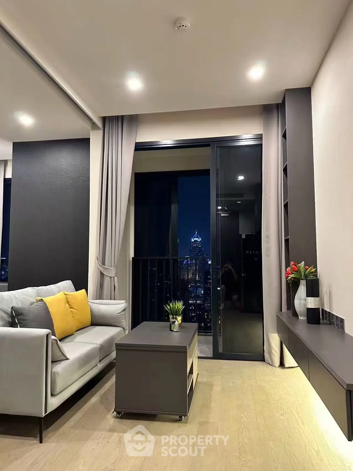 Modern living room with city view, featuring sleek furniture and ambient lighting.