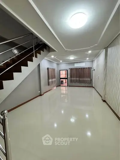 Spacious modern living room with sleek staircase and elegant lighting, perfect for stylish urban living.