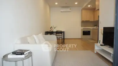 Modern living room with cozy sofa and open kitchen layout in stylish apartment.