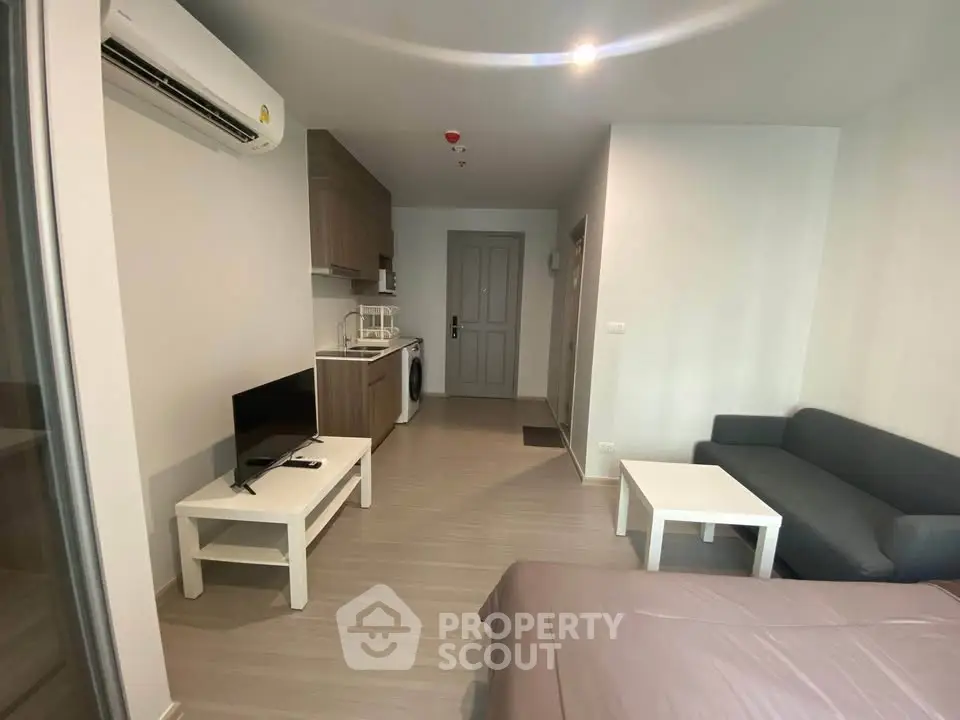 Modern studio apartment with sleek furnishings and open layout, featuring a cozy living area and compact kitchen.