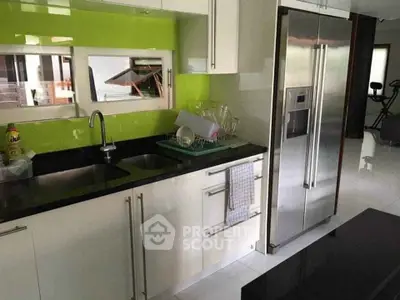Modern kitchen with stainless steel fridge and vibrant green backsplash