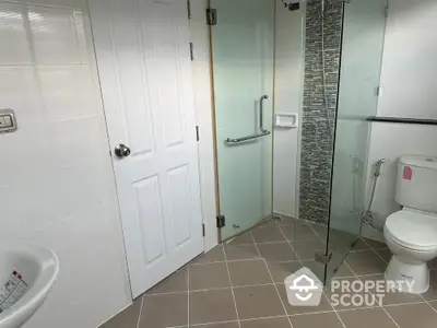 Modern bathroom with glass shower and white fixtures in a stylish home.