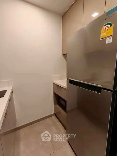 Modern kitchen with sleek appliances and minimalist design, featuring a stainless steel fridge and ample counter space.