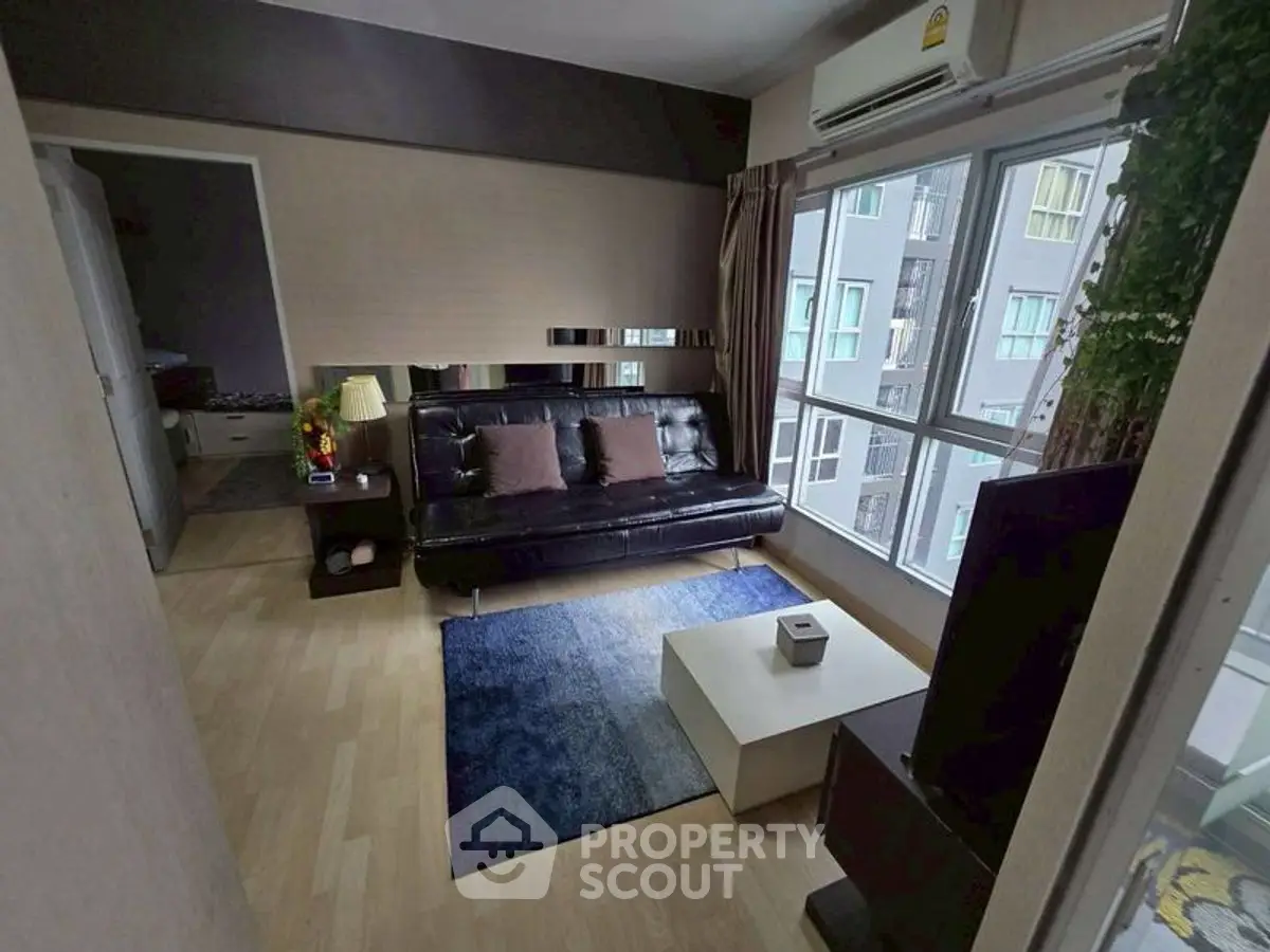 Cozy living room with modern decor and large windows in urban apartment.