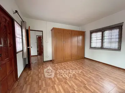 Spacious bedroom with wooden wardrobe and tiled flooring in a well-lit interior.