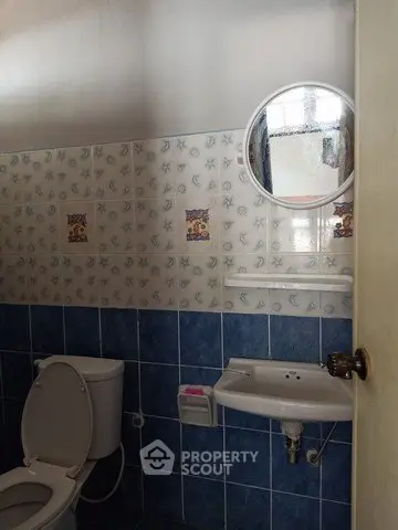 Charming bathroom with nautical-themed tiles and round mirror, perfect for a cozy home.