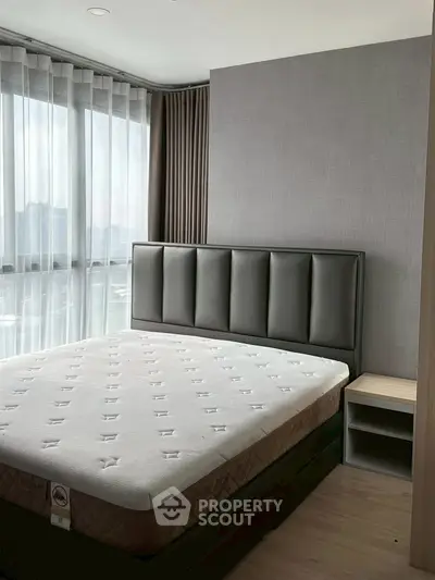 Modern bedroom with large window and stylish headboard in a high-rise apartment.