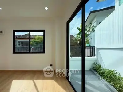 Bright room with large windows and garden view, featuring modern wooden flooring and ample natural light.