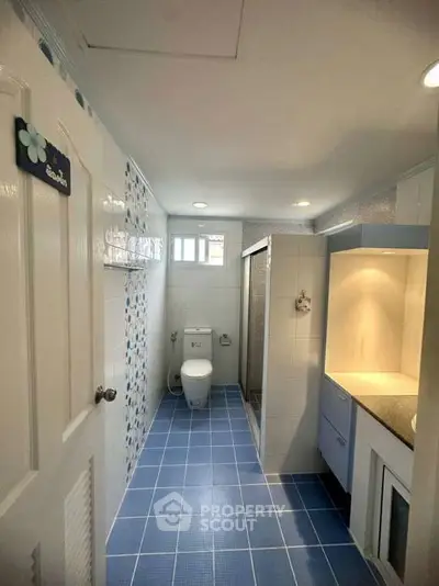 Modern bathroom with blue tiles and sleek fixtures, featuring a shower and toilet.