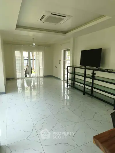Spacious living room with marble flooring and large windows for natural light