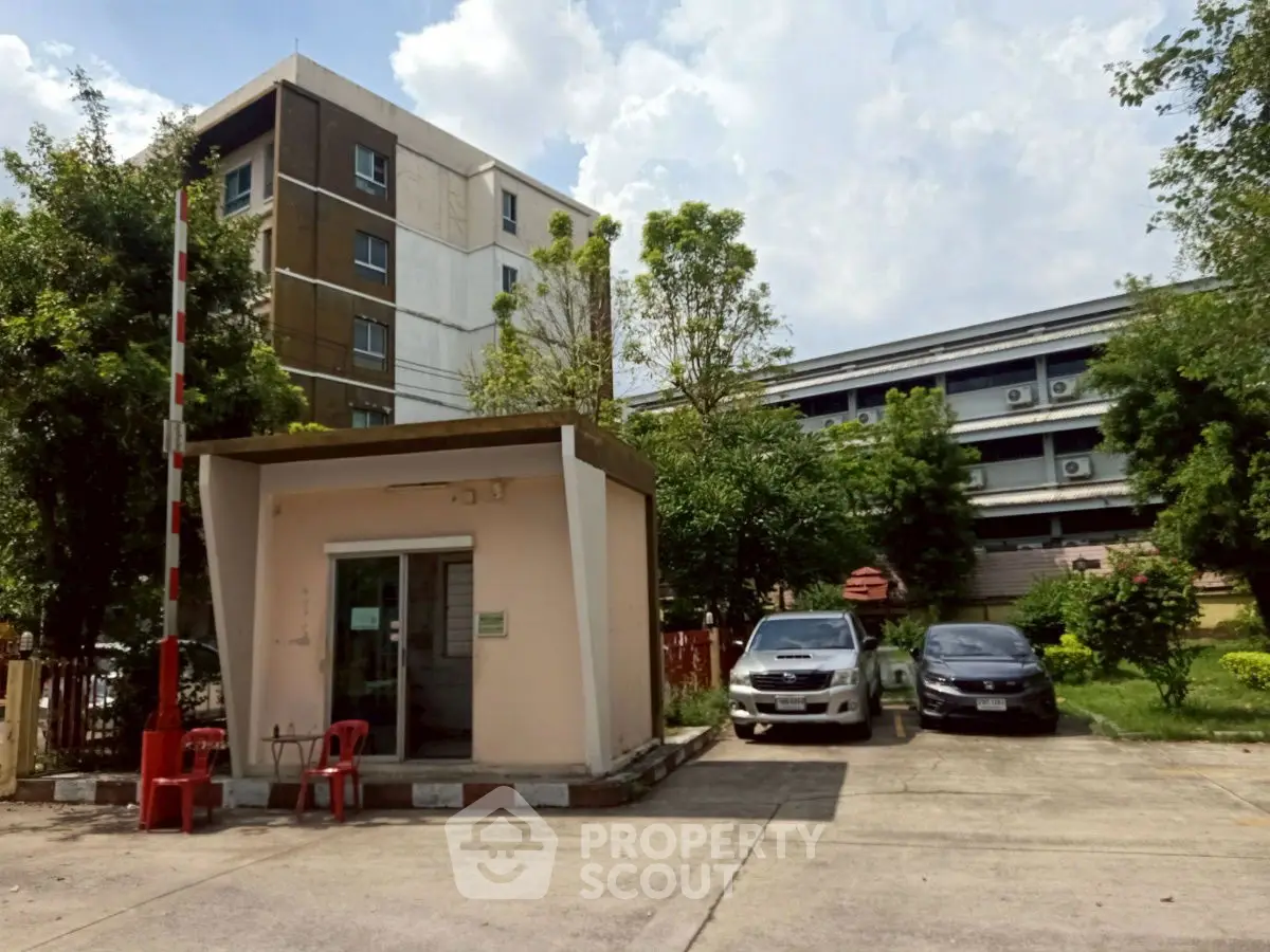 Secure residential parking area with guard booth and lush greenery.